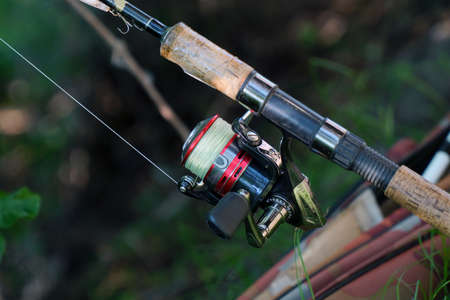 Spinning rod with a reel for catching predatory fish on a natural background