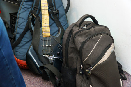 A black guitar, a case and a backpack are the musicians touring equipment in the roomの写真素材