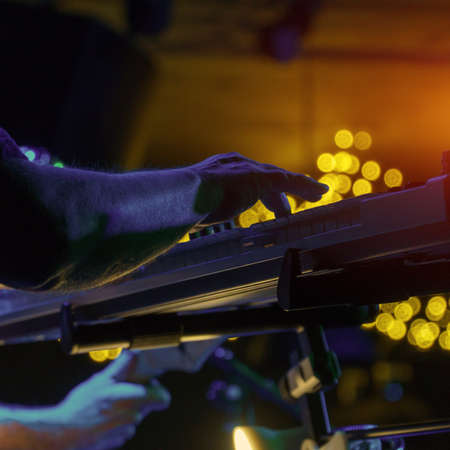 A pianist or keyboardist plays on stage a synthesizer in the spotlight. Dark key. Soft selective focusの写真素材