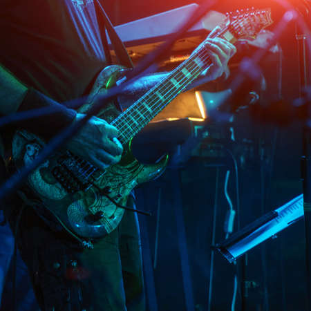 The guitarist plays the guitar in the spotlight. Hands of a Guitar player playing the guitar. Selective focus. Soft focusの写真素材