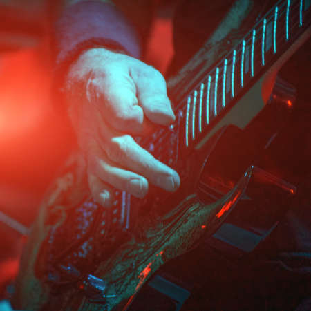 The guitarist plays the guitar in the spotlight. Hands of a Guitar player playing the guitar. Selective focus. Soft focusの写真素材
