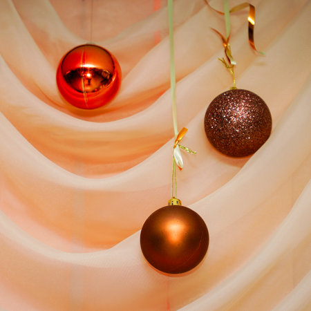 Christmas balls hang on the background of a silk curtainの写真素材