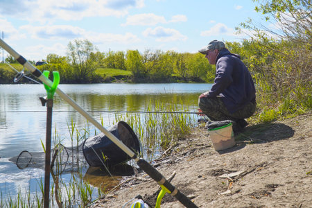 A fisherman on the shore of a lake or river with a fishing rod catches fish. A fisherman throws a fishing rod into the river to catch fishの写真素材