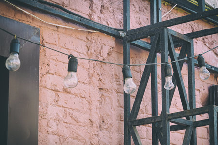 Garlands of simple light bulbs on the background of a brick painted wallの写真素材