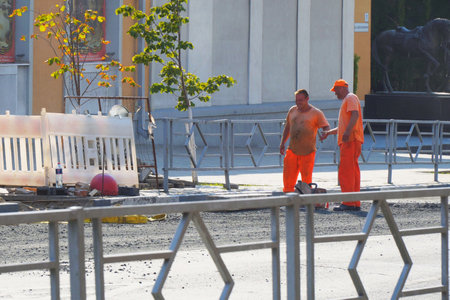 Samara, Russia - circa March, 2022: Uniformed road workers work on a city street laying a curbのeditorial素材
