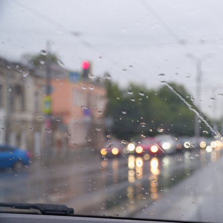 Cars standing in a traffic jam on a city street in rainy weather. View through the windshield. Blurred viewの写真素材