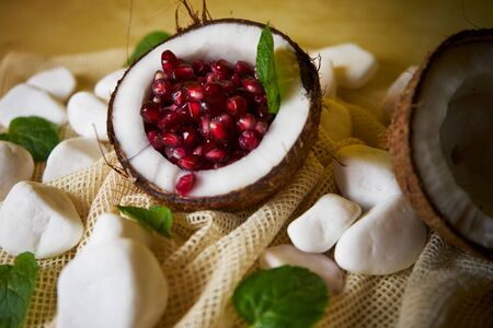 A proposal to serve a pomegranate fruit in a coconut. Health and vitamins, great colors, the way fruit is served.の写真素材
