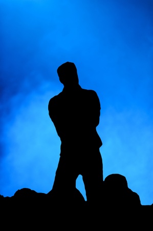 Silhouette of a man singing on stage in front of an audience against a blue backgroundの写真素材