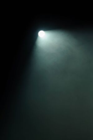 Single shining spotlight at night with its beam pointing at a tangent to the right hand corner of...