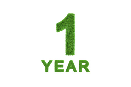 Decorative three-dimensional 1st anniversary or birthday celebration numeral with the number and text in textured fresh green grass for an eco-friendly greeting card or congratulationsの写真素材