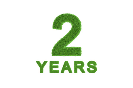 Decorative three-dimensional 2nd anniversary or birthday celebration numeral with the number and text in textured fresh green grass for an eco-friendly greeting card or congratulationsの写真素材