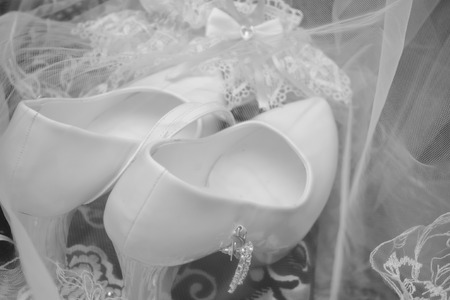 A wedding gentle bouquet of white and pink roses and high-heeled shoes on a green grass in the park.の写真素材