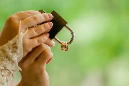 Gold wedding lock in couples hands. Bride holding a bright wedding bouquet with differentの写真素材
