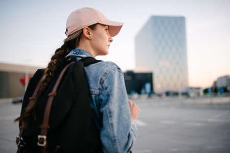 Tourist girl with her backpack looking at city landscape, back view Adventure and travel in the concept . Backpack rear view. Tourism in city.の写真素材