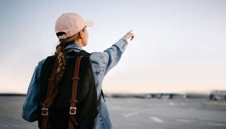 Horizontal shot of female points with fore finger away, indicates copy space. Pointing with fingers at street. Moving forward gesture. Check this out.の写真素材