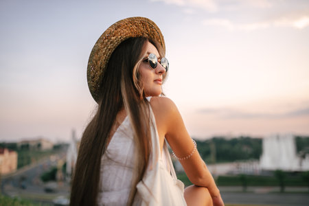 Portrait of a relaxed woman with hat looking forward at the horizon cityscape in the background copy spaceの写真素材
