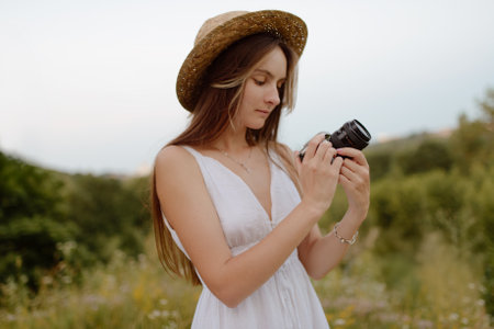 Captivating young woman holding a camera while enjoying her time in the beautiful natureの写真素材