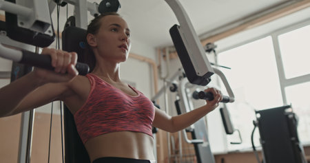 A woman focused on strength training at the gym using a weight training machine