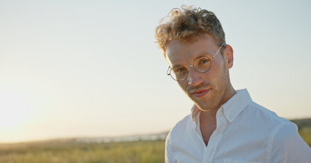 A man wearing a white shirt is posing gracefully in nature during a stunning sunsetの写真素材