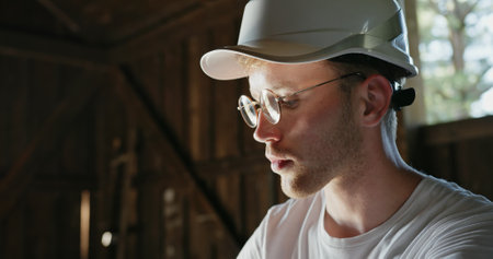 A Focused Construction Worker Wearing a Hard Hat and Glasses Engaged in His Taskの写真素材