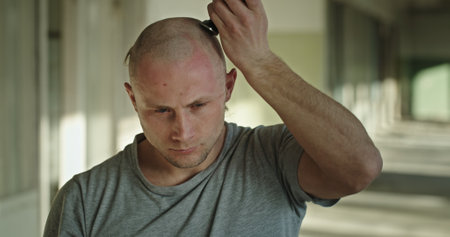 A man shaves his head peacefully, displaying a tranquil expression in an urban setting