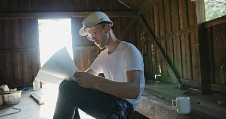A Young Man Engaged in Reading Plans inside a Rustic Workshop Brimming with Creativity and Tools