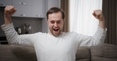 A Very Excited Man Celebrating His Significant Success and Happiness in the Comfort of His Homeの写真素材