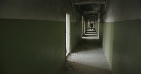 This is an eerie and atmospheric abandoned hallway with a couple of open doors visibleの写真素材
