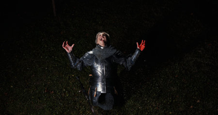 An Eerie Figure Dressed in a Metallic Costume Stands in a Dark and Foreboding Forestの写真素材