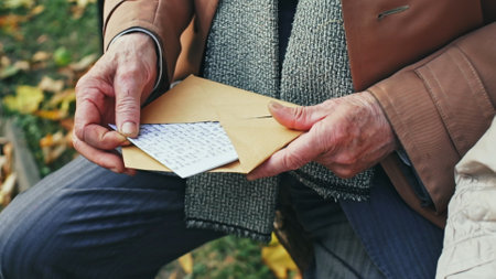 Elderly man opening handwritten letter in park