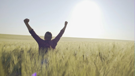 Happy farmer on the field of young wheat on the background of the sunrise - slow motion
