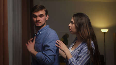 Couples Tense Moment: Woman Confronting Man Over Secretive Phone Useの写真素材