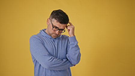 Senior man with glasses on a yellow background crossing his arms in refusal