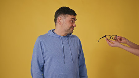 Charming senior man with glasses on a yellow background playfully asking for a call back