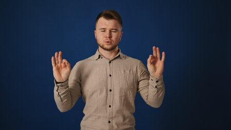 Man in Zen Pose Seeking Tranquility Against Blue Background