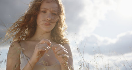 Pensive Red-haired Woman Holding Wheat in Field