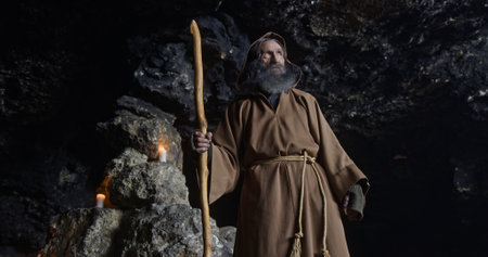 A Mystical Figure is found deep within a dark, enchanting Cave, holding a Staff
