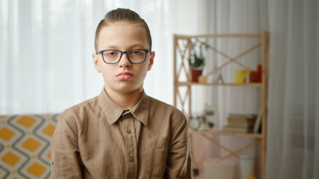 A Serious Young Boy Wearing Glasses in a Cozy Home Setting and Surrounded by Comforts