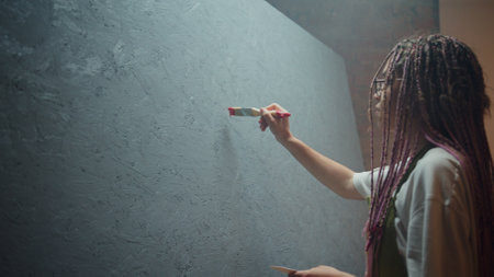 A passionate creative individual skillfully painting a wall in a stylish modern space with flair
