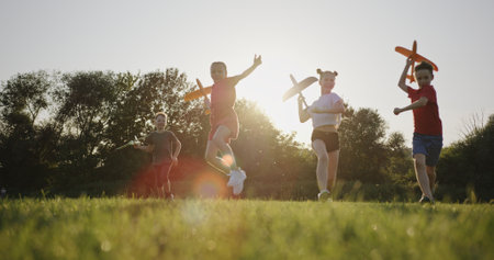 Joyful Kids Launching Toy Airplanes on Lush Meadow at Sunset, Slow Motion