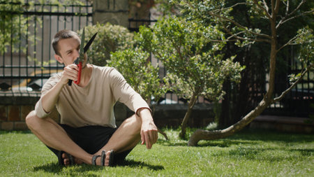 A Thoughtful Man is Sitting in a Beautiful Garden, Engaged with His Device