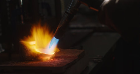 Goldsmith melting gold in crucible with blow torch