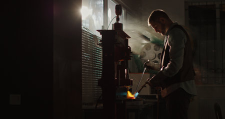 Professional male jeweler melting gold in workshop