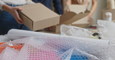 Hands Preparing Cardboard Boxes for Shipment in a Busy Home Office