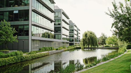 Modern office complex with glass fronted buildings in a scenic landscaped garden with pond ad...