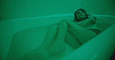 An Eerie Green Bathtub Scene Featuring a Troubled Subject and Capturing Complex Emotions
