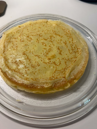 A delicious, fluffy golden pancake beautifully presented on an elegant glass plate