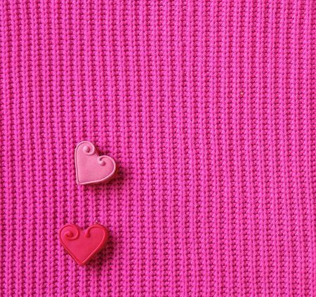 Two gingerbread hearts are n a soft pink knitted backgroundの写真素材