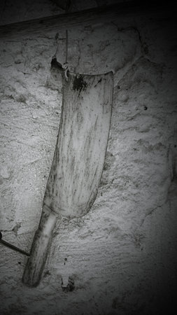 An antique, rusty knife hangs on the wall as a decorative piece, showcasing its age and history. This knife, specifically designed for slicing cabbages, adds a unique touch to the garden design.の写真素材