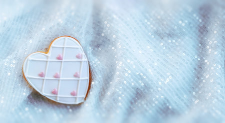 Valentine's Day Design. White Gingerbread Heart on a Light Background with Sequins. A Magical Holiday Atmosphere. The concept of Valentine's Day. Flat Lay. Top View. Copy Space. Web Bannerの写真素材